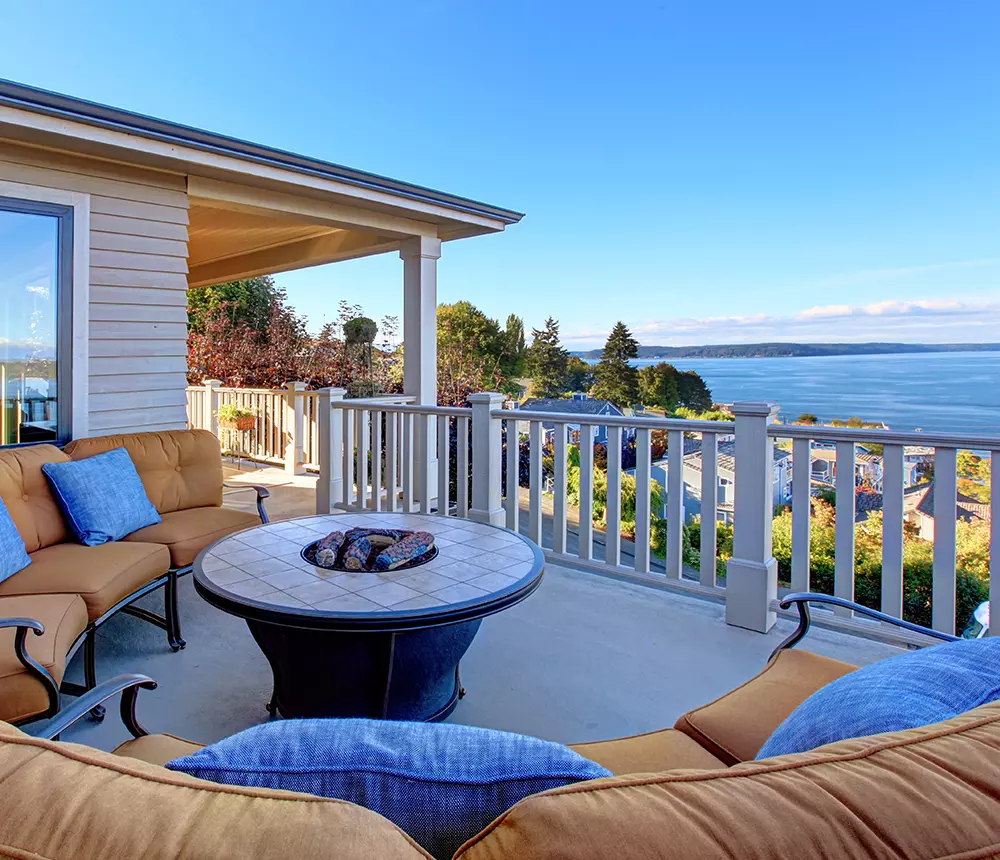 Large deck with cozy chairs and fire pit overseeing a big lake near Vancouver