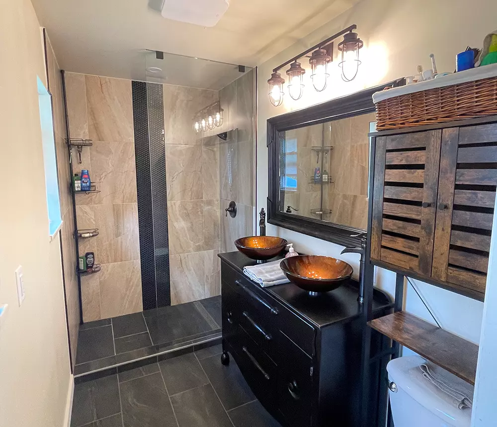 Bathroom renovation for Metro Vancouver with dark floors, cream marble, and golden sink