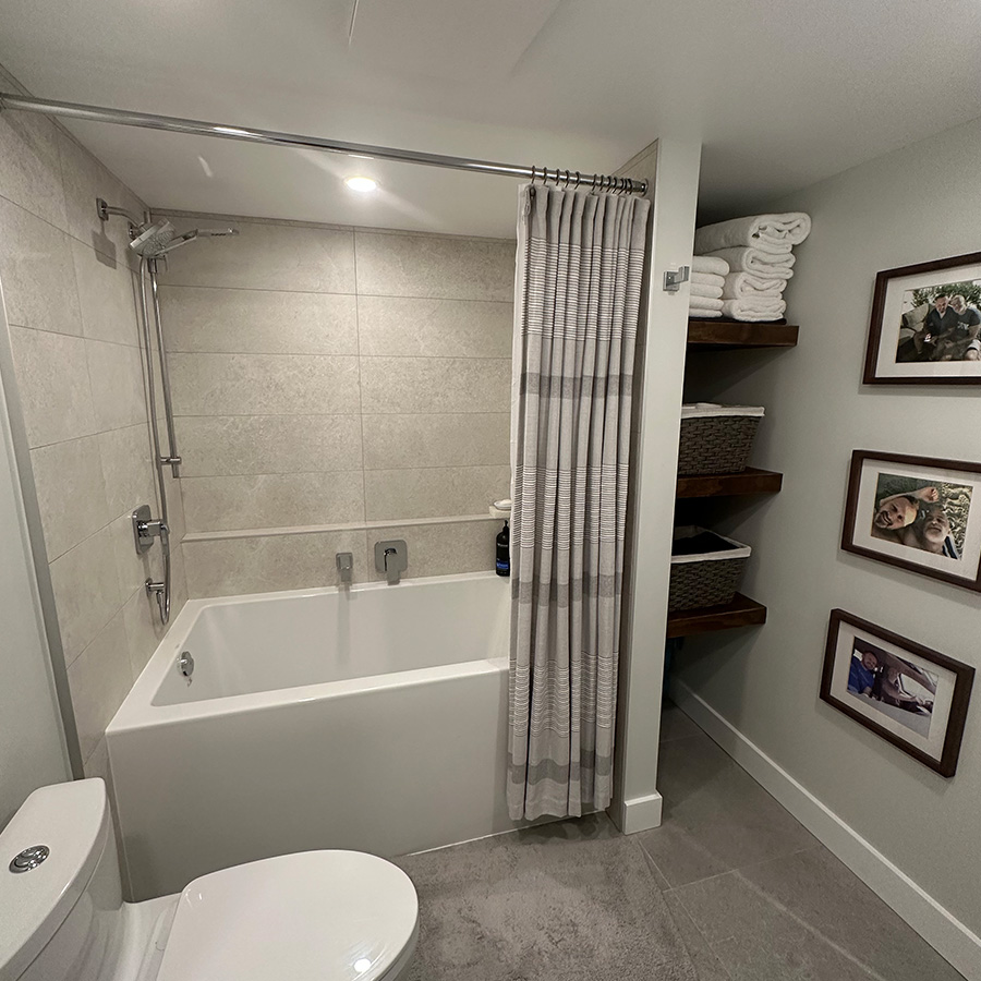 A tub to shower combo with a shower curtain and open shelving for towels