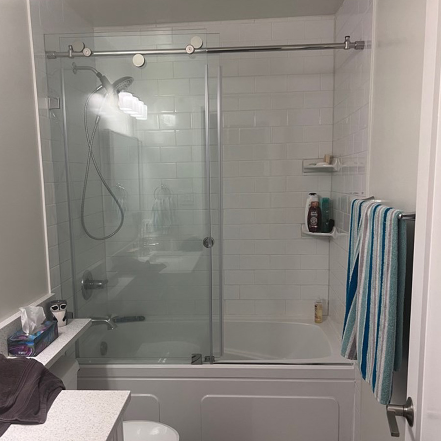 A dated tub and shower combo with glass sliding doors