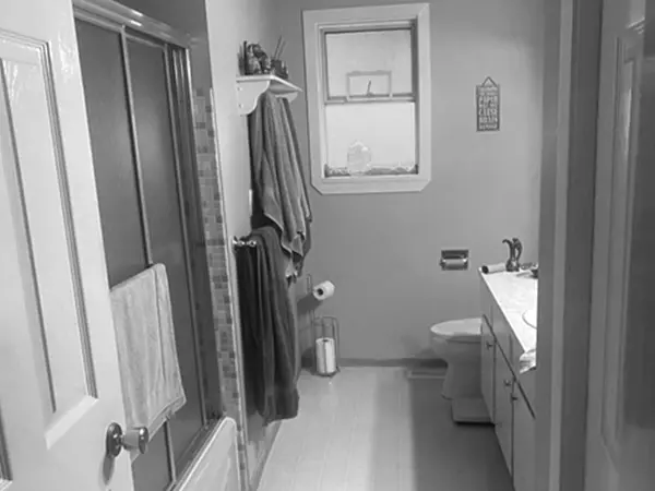 View of outdated and tight bathroom with old metal shower doors and single sink