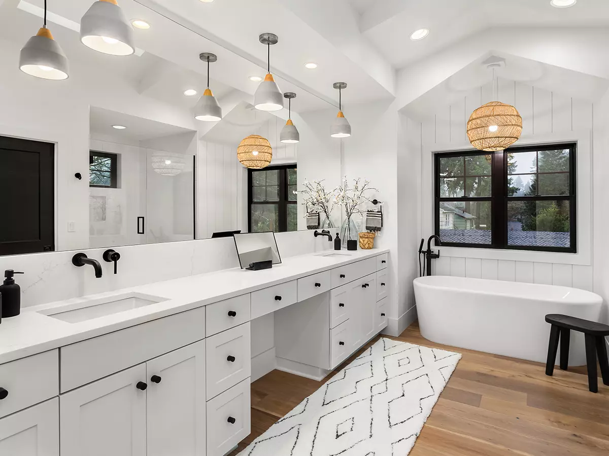 Modern all white bathroom with large black window and black accents on the double sinks