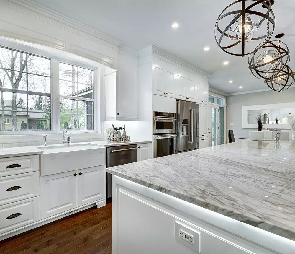 Luxury white kitchen renovation with open space, big island with quartz countertop, and big windows