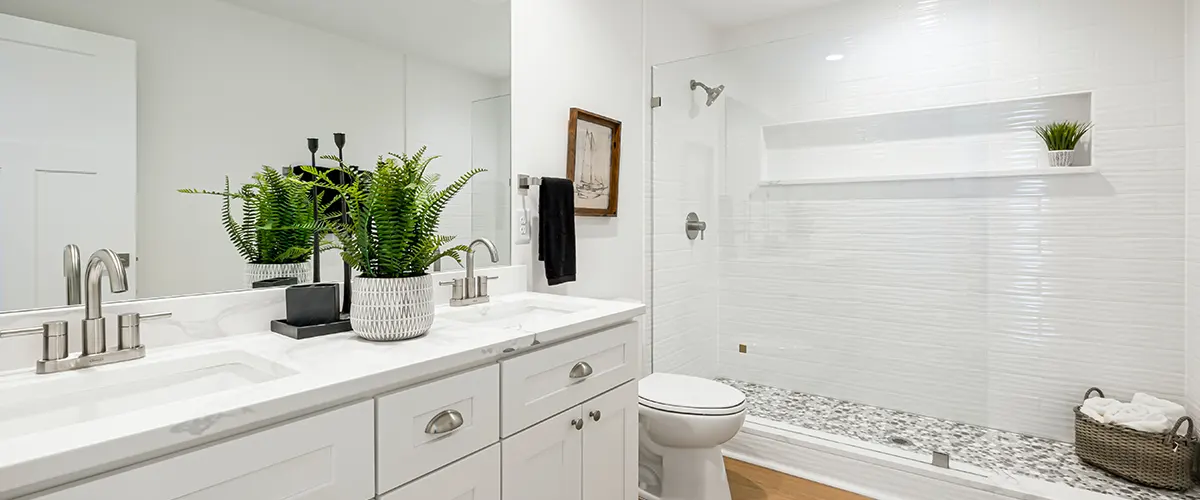 All white bathroom renovation with white cabinets, white walls, and white shower with glass enclosure