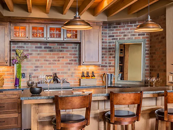 Rustic kitchen renovation with wood beams, wood island, and brick walls and backsplash