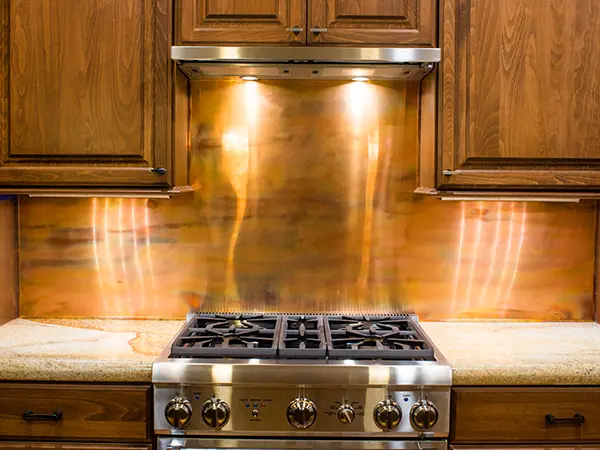 Copper backsplash in rustic kitchen renovation with brown wood cabinets