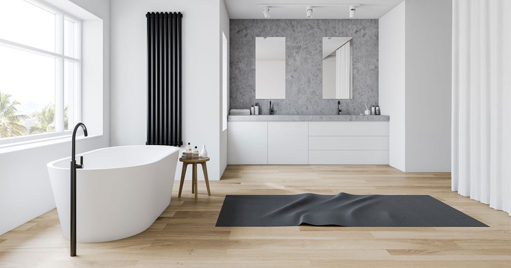 A white tub with dark water fixture and a black bath floor matt