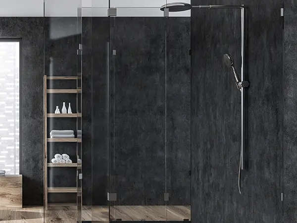 A glass walk-in shower with dark tile surround