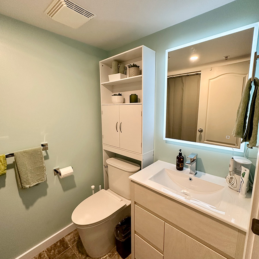 Light green walls in a bathroom with cabinets and vanity