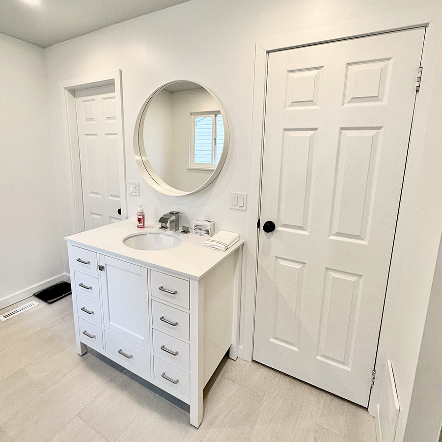 A white bathroom with a vanity and two doors on each side of it