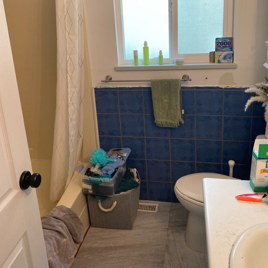 A dated bathroom with blue tile on walls and a tub with a curtain