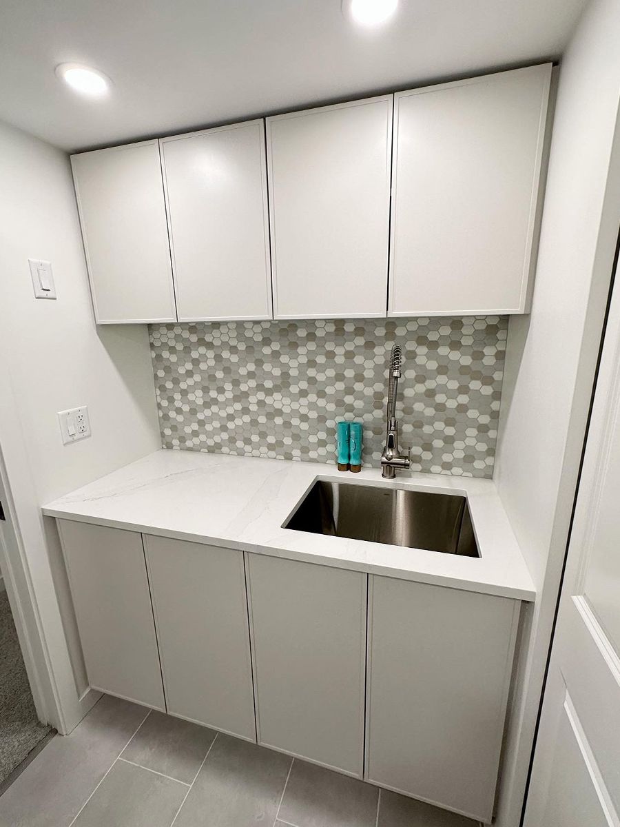 A small kitchenette with a tile backsplash and a quartz countertop