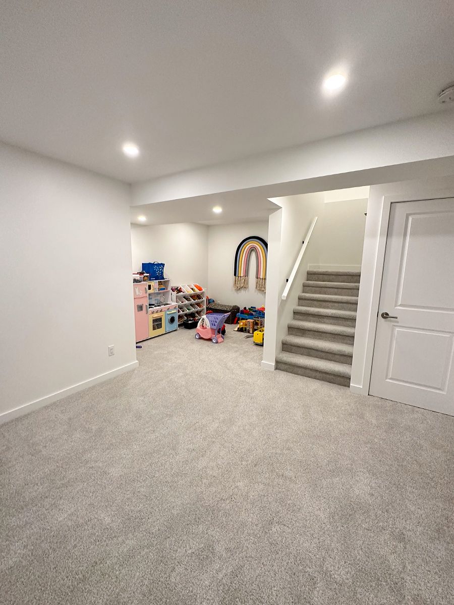 Basement remodel with carpet flooring and a corner dedicated to children toys