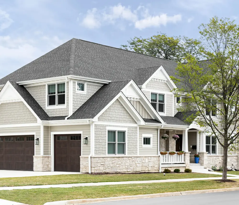A large home with stone veneer and beautiful light gray siding
