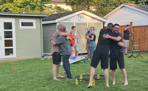 Group of friends celebrating outdoors, enjoying games and camaraderie in a backyard setting, highlighting the importance of maintaining a safe home environment during holiday gatherings.